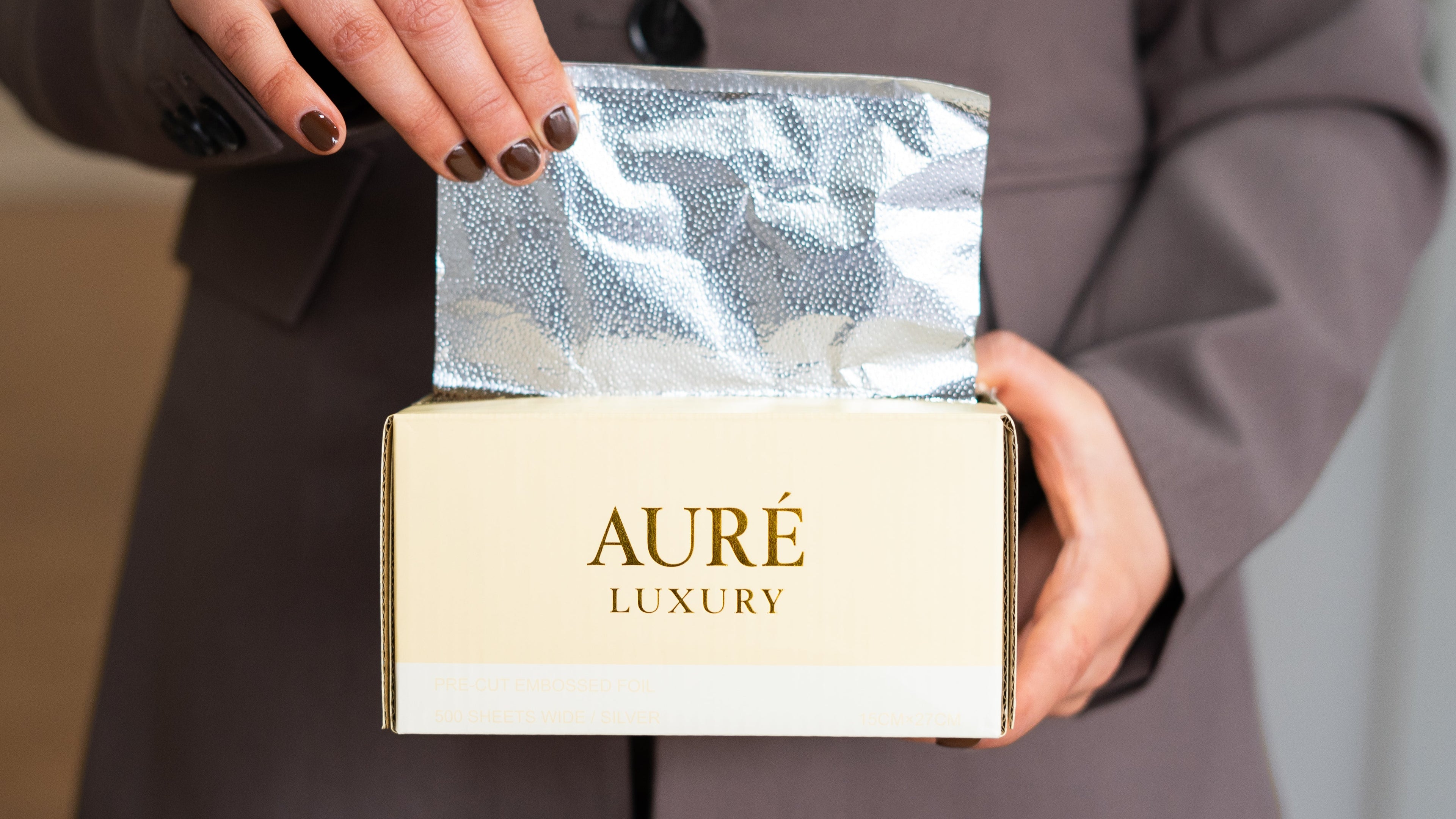 Person holding a box with 'Aureé Luxury' branding