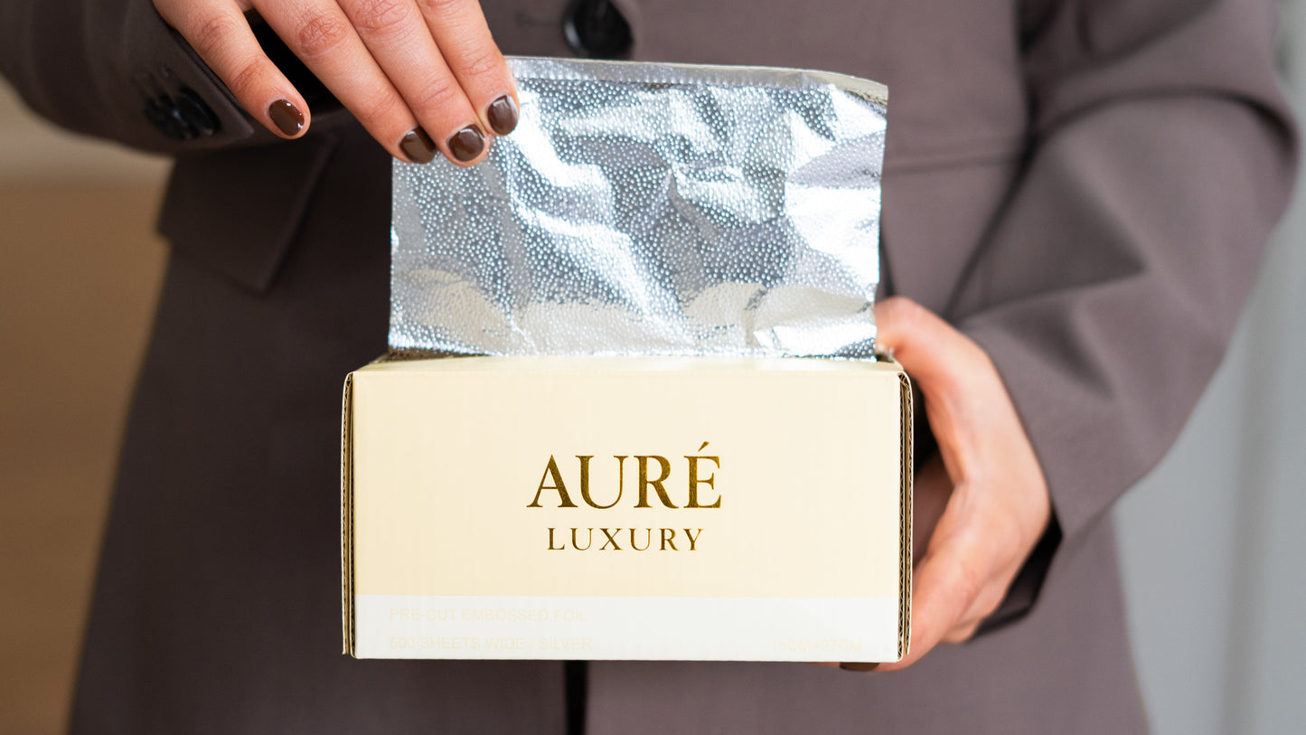 Person holding a box with 'Aureé Luxury' branding