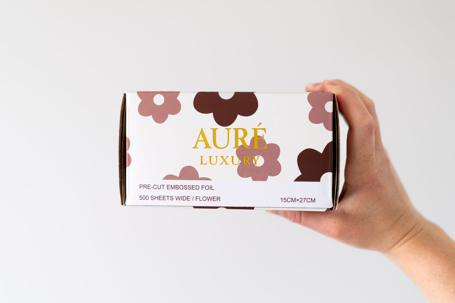 Hand holding a box of Aure Luxury pre-cut embossed hair foils design for salons in australia
